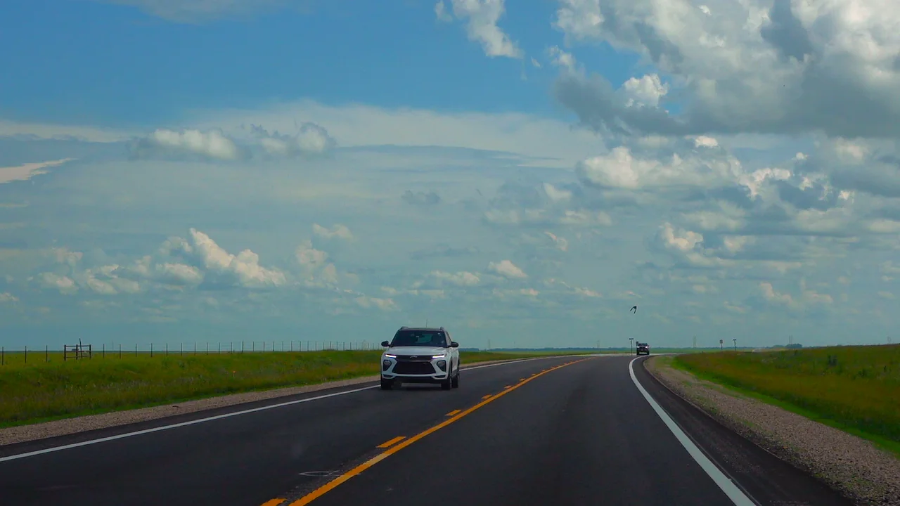 Straight Kansas road under huge clouds