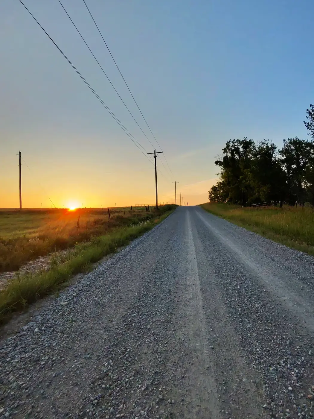 Power-line gravel road at sunrise