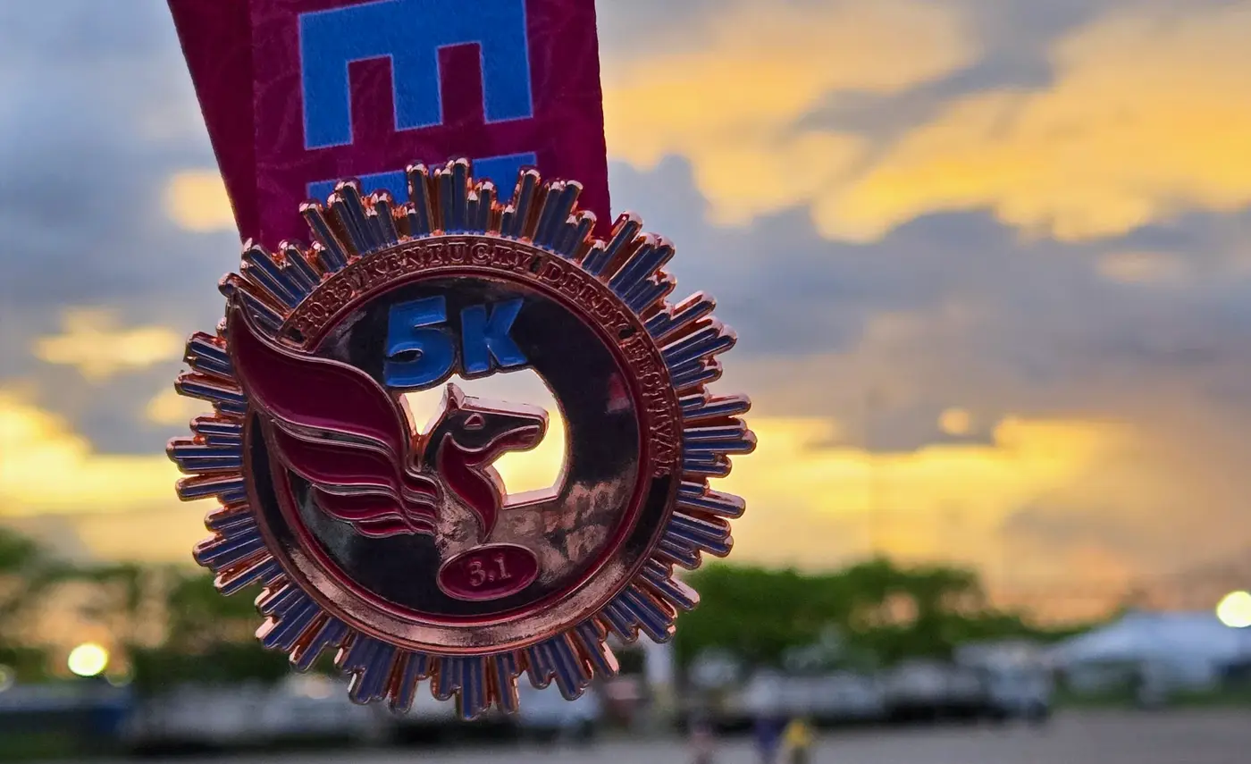 5K medal held against the sunset