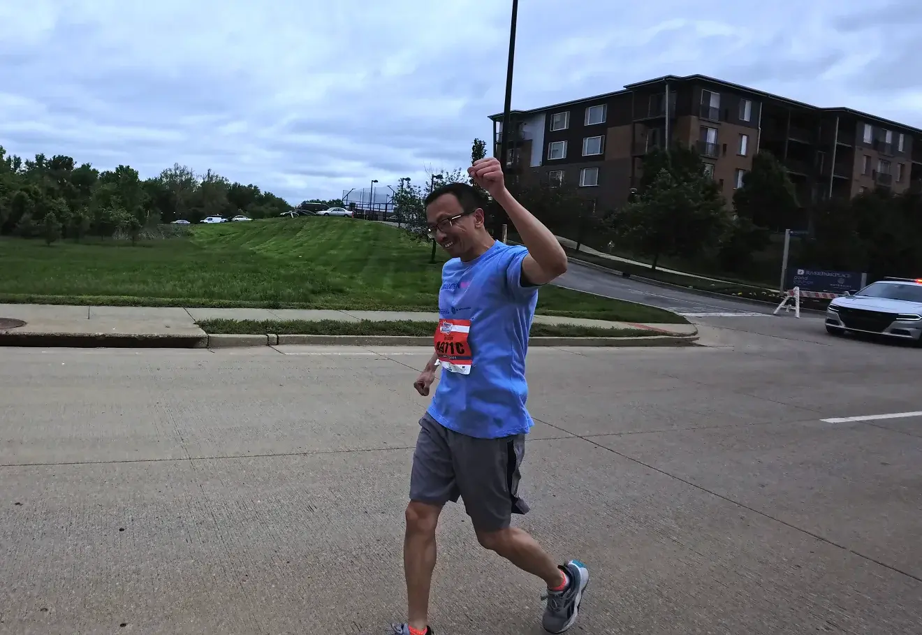 Runner raising a hand on the long road