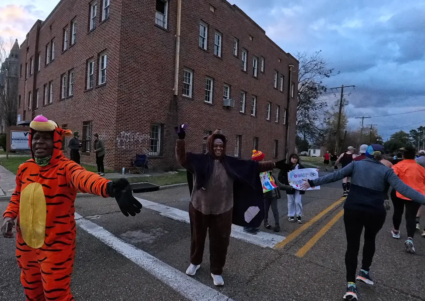 A costumed dinosaur cheering at the roadside