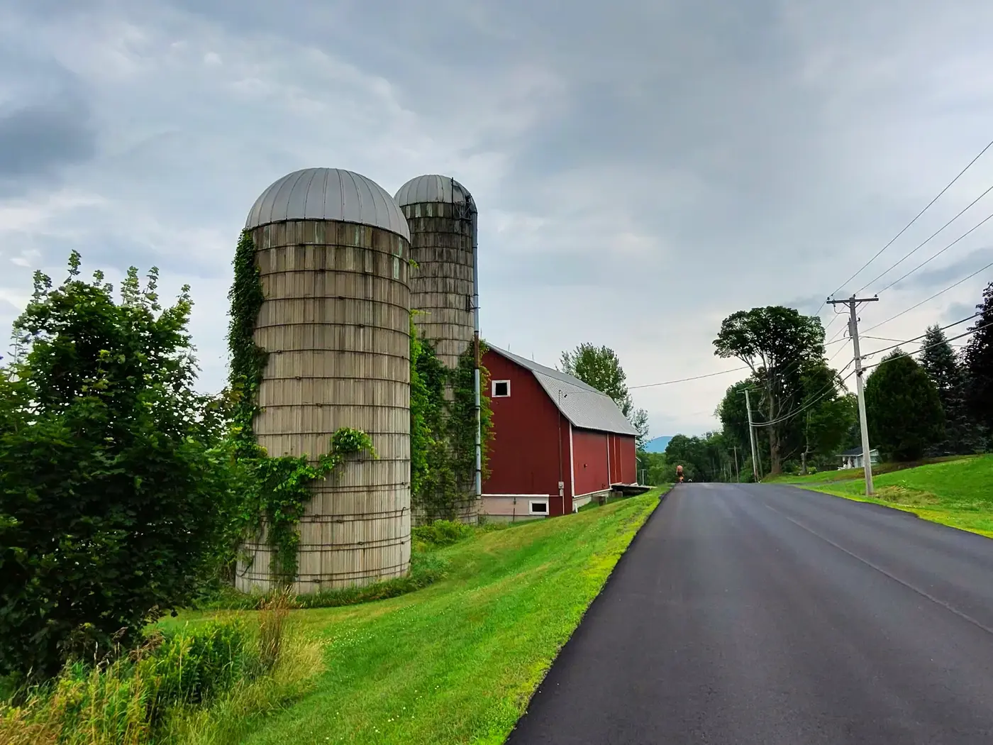 Twin silos and a red barn by the road