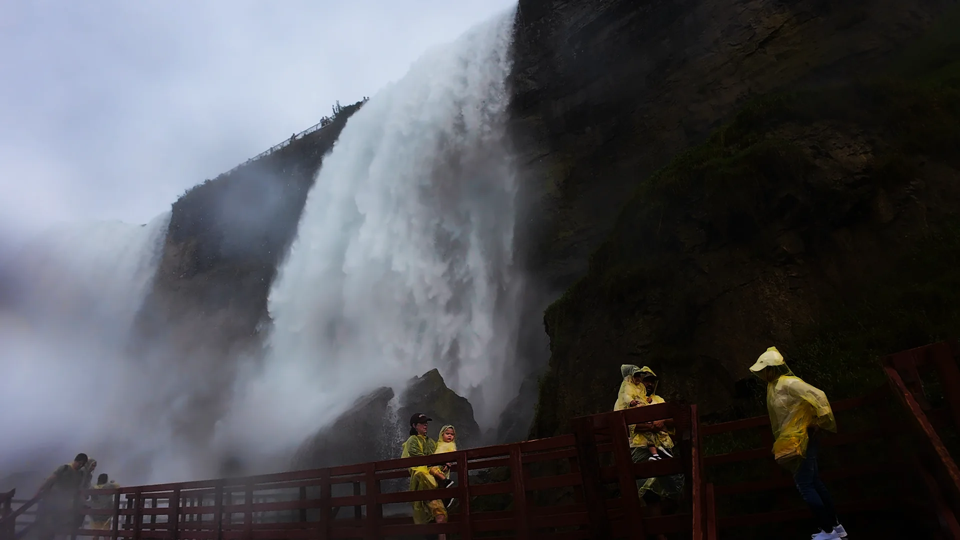 Visitors in ponchos beneath the falls