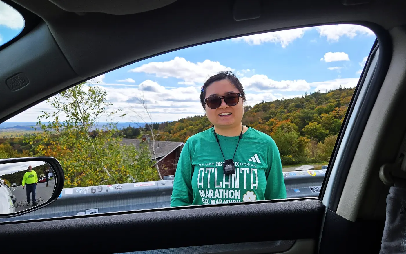 Siqi framed by autumn hills from the car